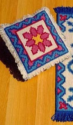 A finished Arraiolos cushion with pink flower motif