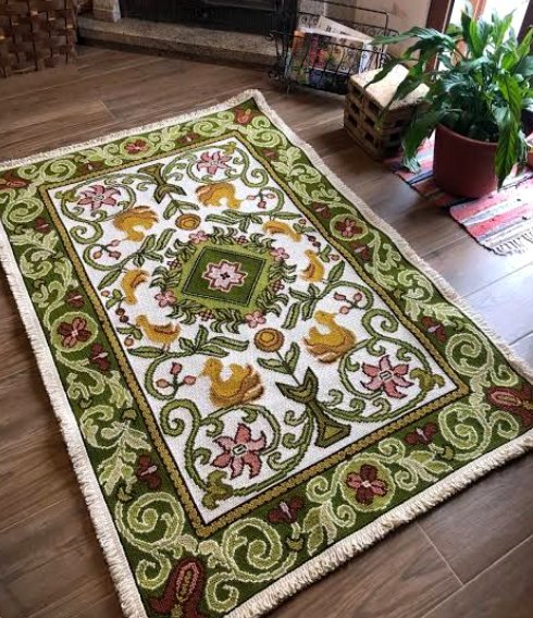 A green and cream Arraiolos rug by a fireplace